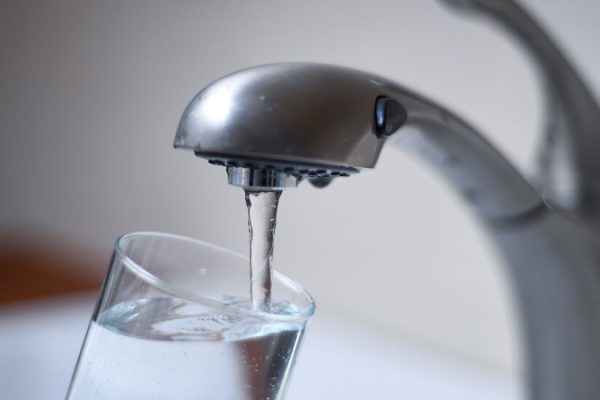 an open tap letting water flow into a glass