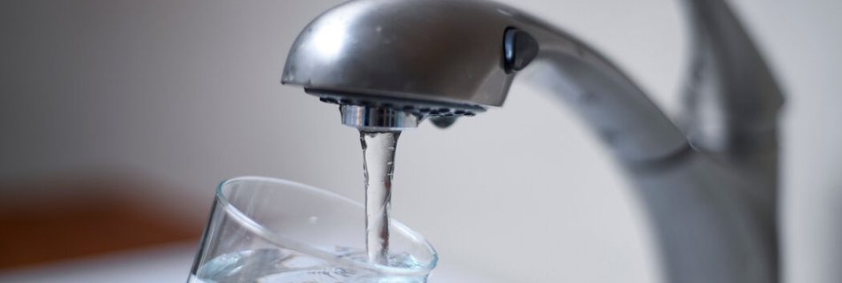 an open tap letting water flow into a glass