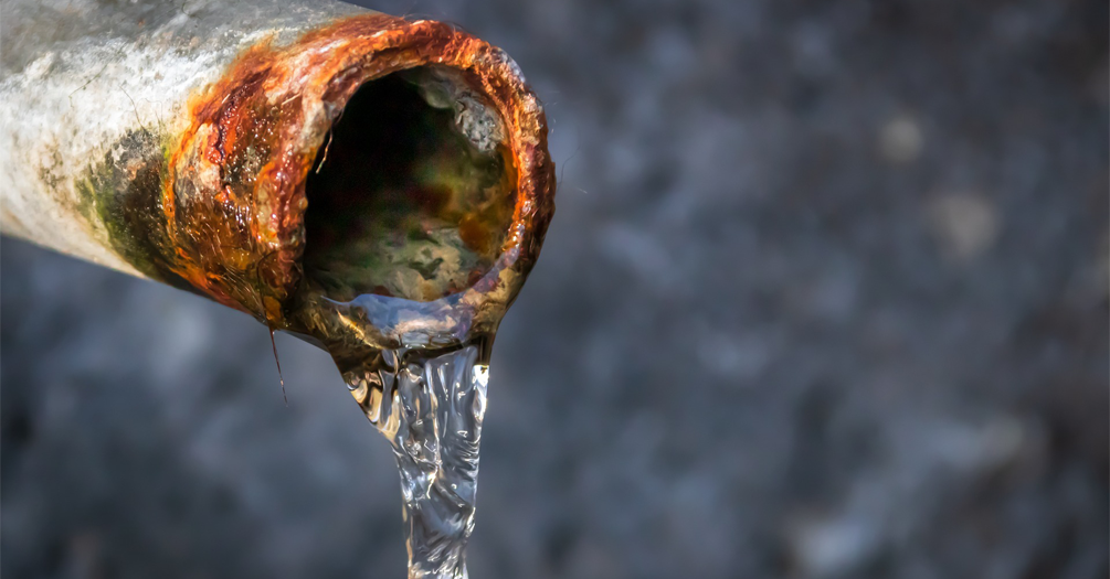 a rusted metal pipe with water flowing out it