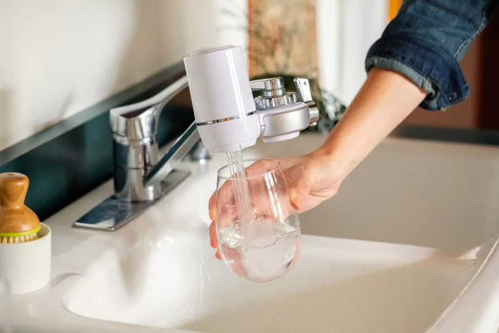 a person holding a glass under running filtered water