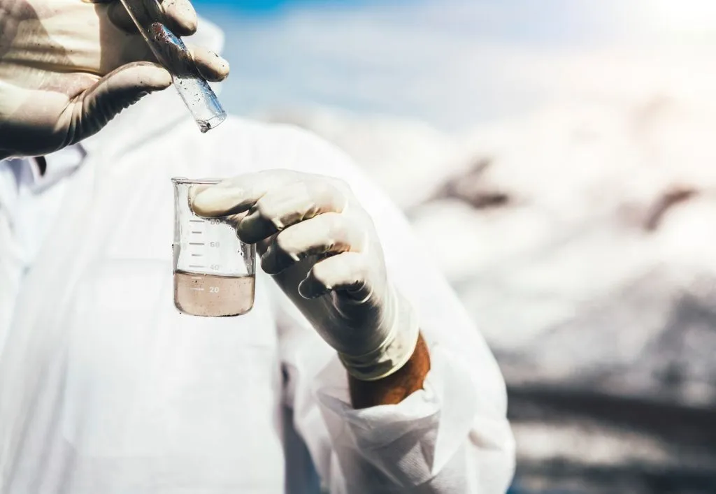 scientist pouring a liquid into a beaker to test the water